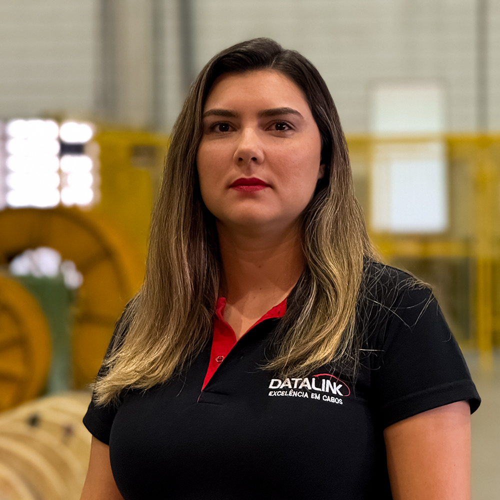 Esta imagem mostra nossa vendendora Cindy dos Santos vestindo uma camisa polo preta e vermelha com o logotipo “Datalink, Tecnologia em cabos”, em um fundo branco.